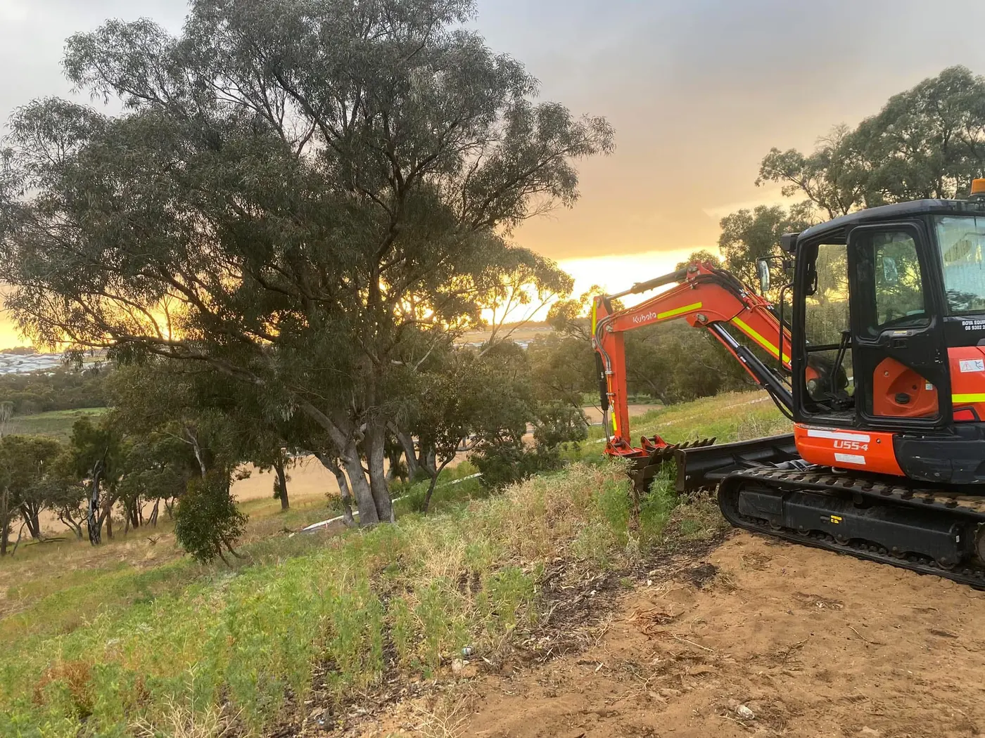AV Civil Earthworks excavator clearing a block at sunset