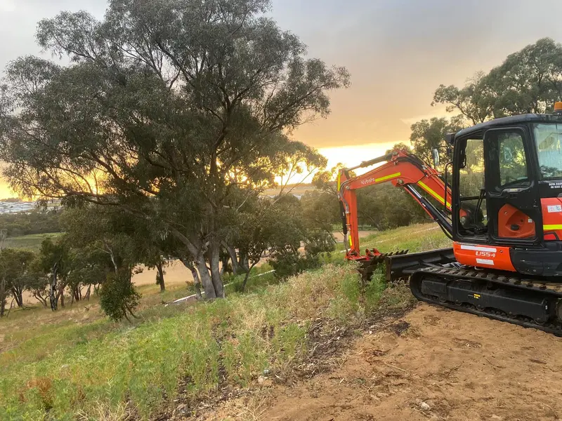 AV Civil Earthworks excavator clearing a block at sunset