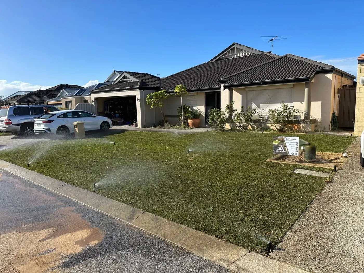 Fresh roll-on lawn with sprinklers running in front yard