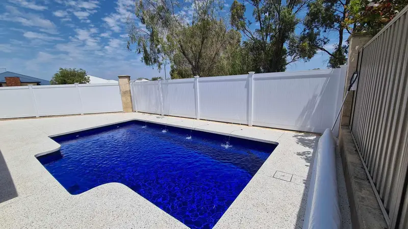 Exposed aggregate pool surround with seamless edging around a blue pool